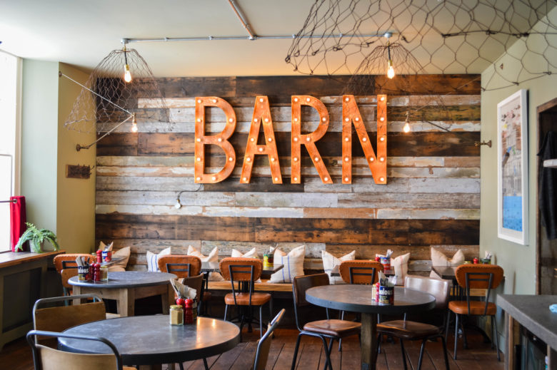 The restaurant room with a large sign that says "Barn" on the back wall