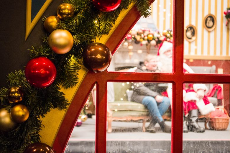 A window adorned with baubles and through the glass you can see Santa sitting with a visitor - Tivoli Gardens, Copenhagen