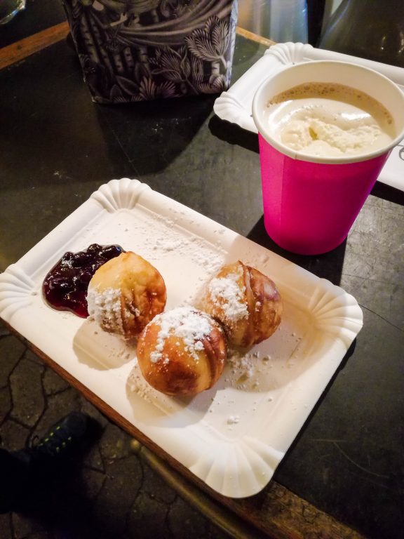 A plate of aebelskiver and a cup of lumbumba at a Christmas market in Copenhagen