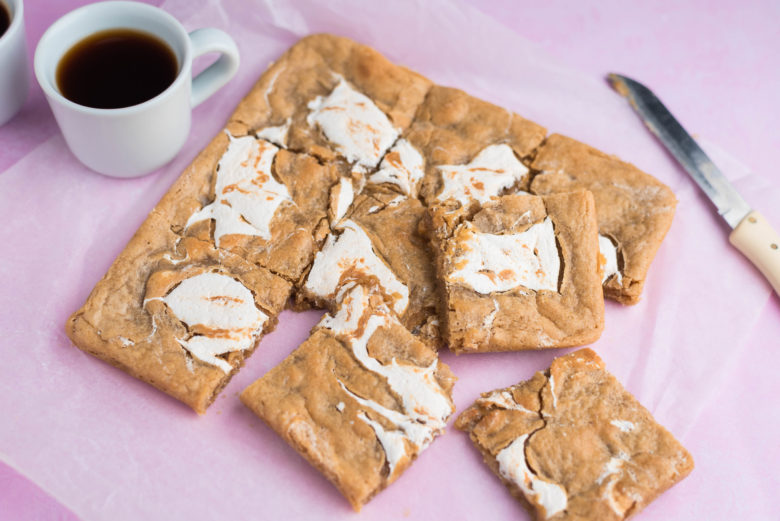Photo of Fluffernutter Bars cut up into squares alongside cups of coffee