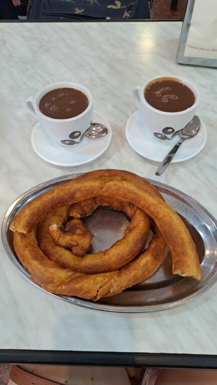 A plate filled with churros and two cups of hot chocolate