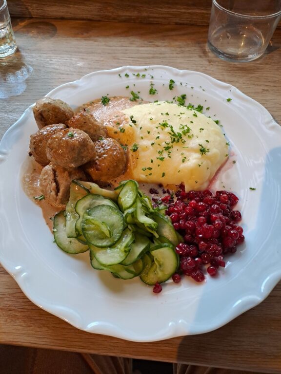 what to eat in Stockholm - photo of a plate of meatballs, mashed potato, cucumber salad and lingonberries