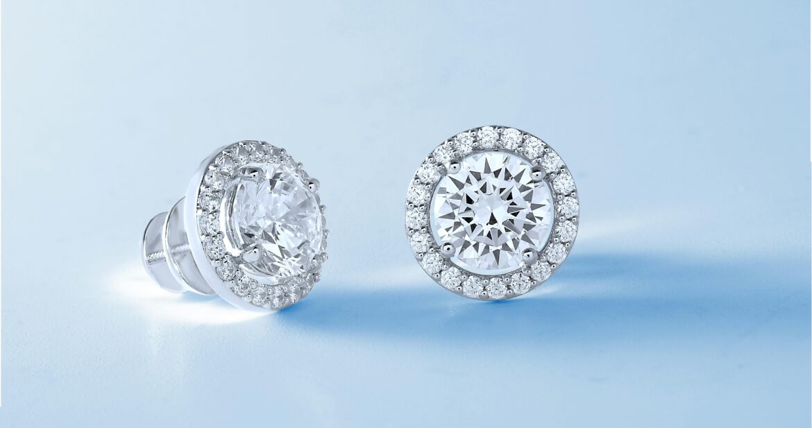 Two diamond and silver stud earrings on a blue background