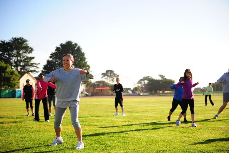 A group of people exercising in a sunny park