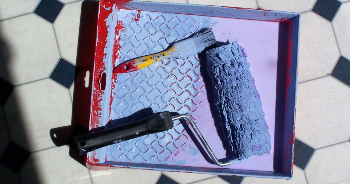 paint roller in blue paint on tile floor