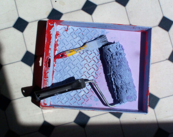 paint roller in blue paint on tile floor