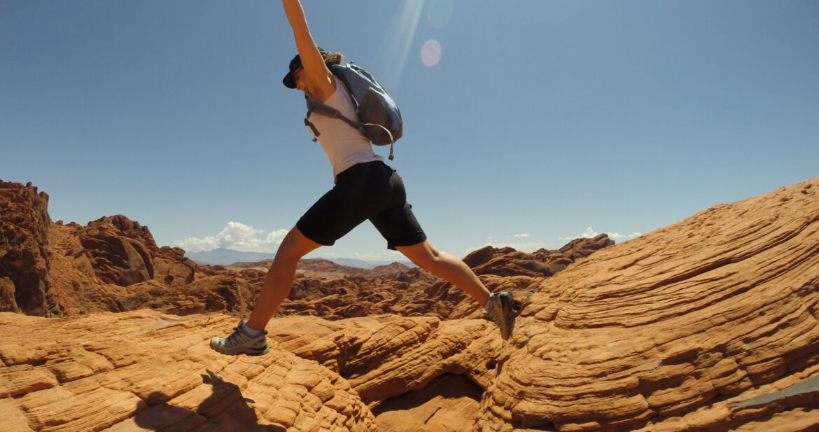 woman jumps across rocks