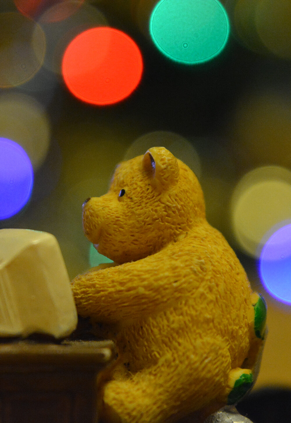 Toy teddy bear sitting at a computer