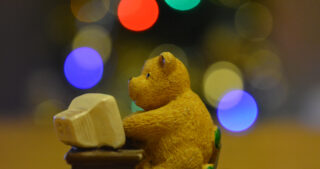 Toy teddy bear sitting at a computer