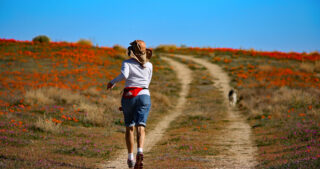 woman runs in field with dog