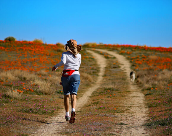 woman runs in field with dog