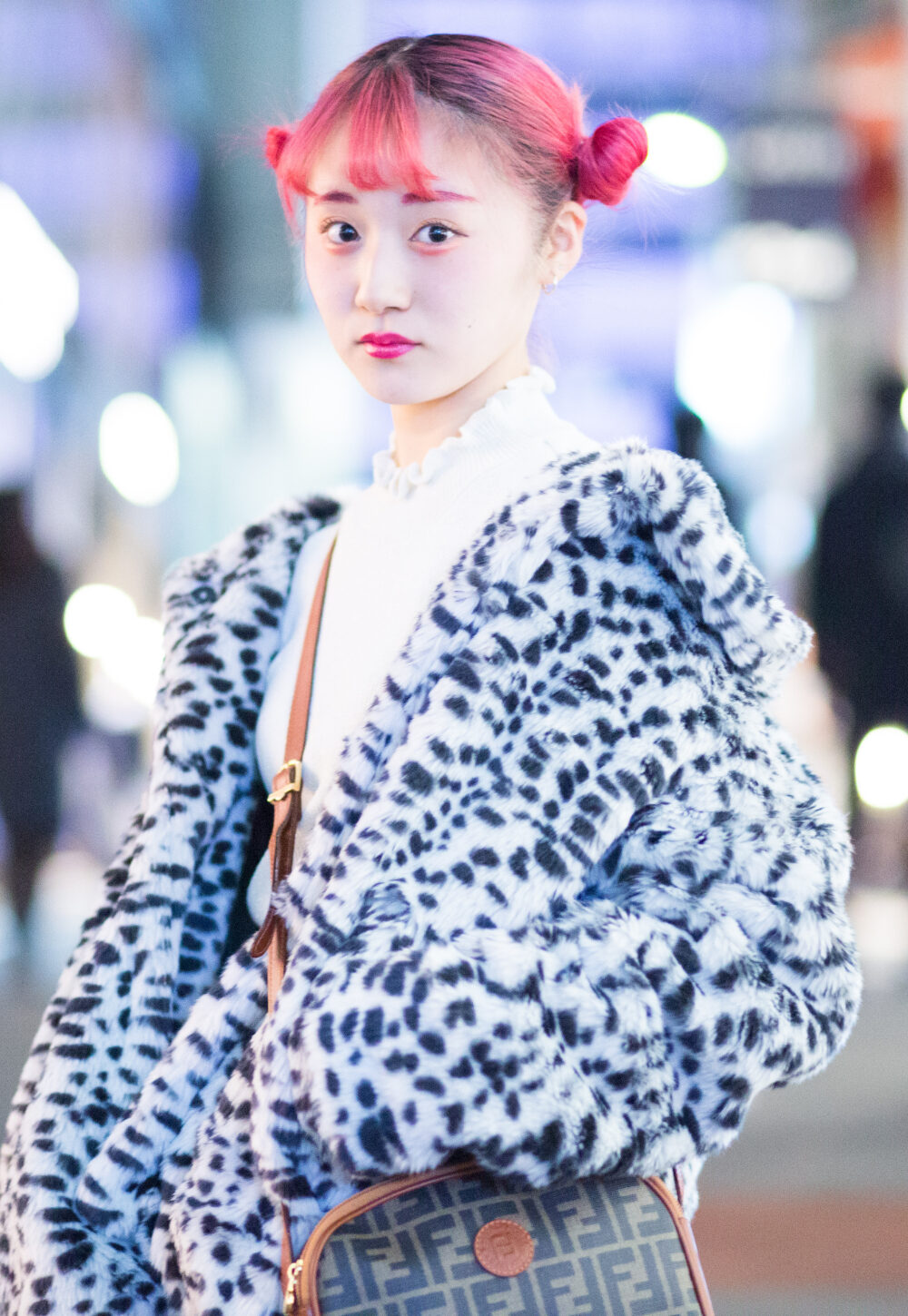 woman with bright pink hai and funky jacket on busy shopping street