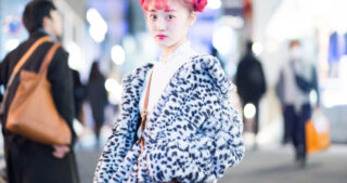 woman with bright pink hai and funky jacket on busy shopping street
