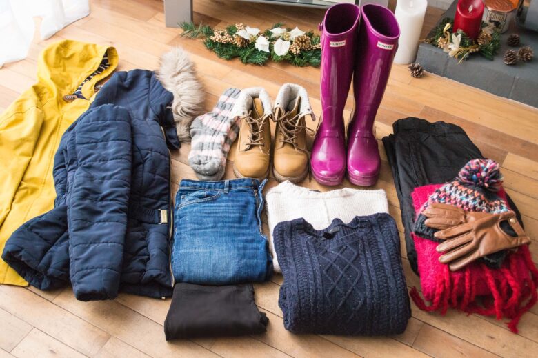 Selection of winter clothing and shoes laid out on a floor ready for packing