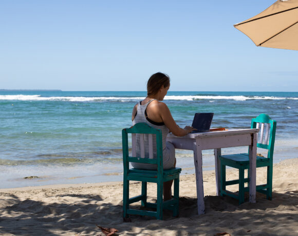 Woman working on a laptop at a table on the beach