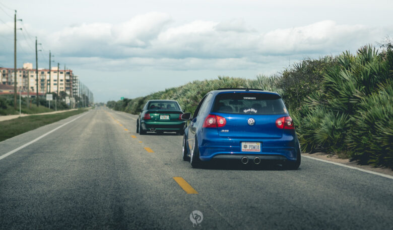 Cars driving down the road with palm trees to the side