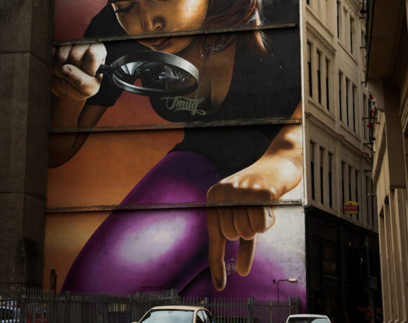 street art of woman inspecting cars with magnifying glass.
