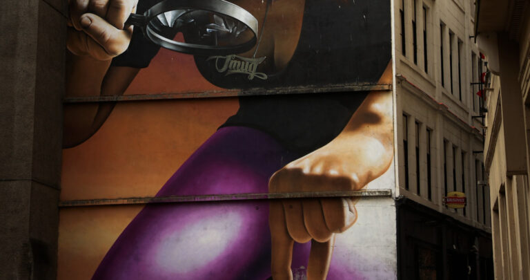 street art of woman inspecting cars with magnifying glass.