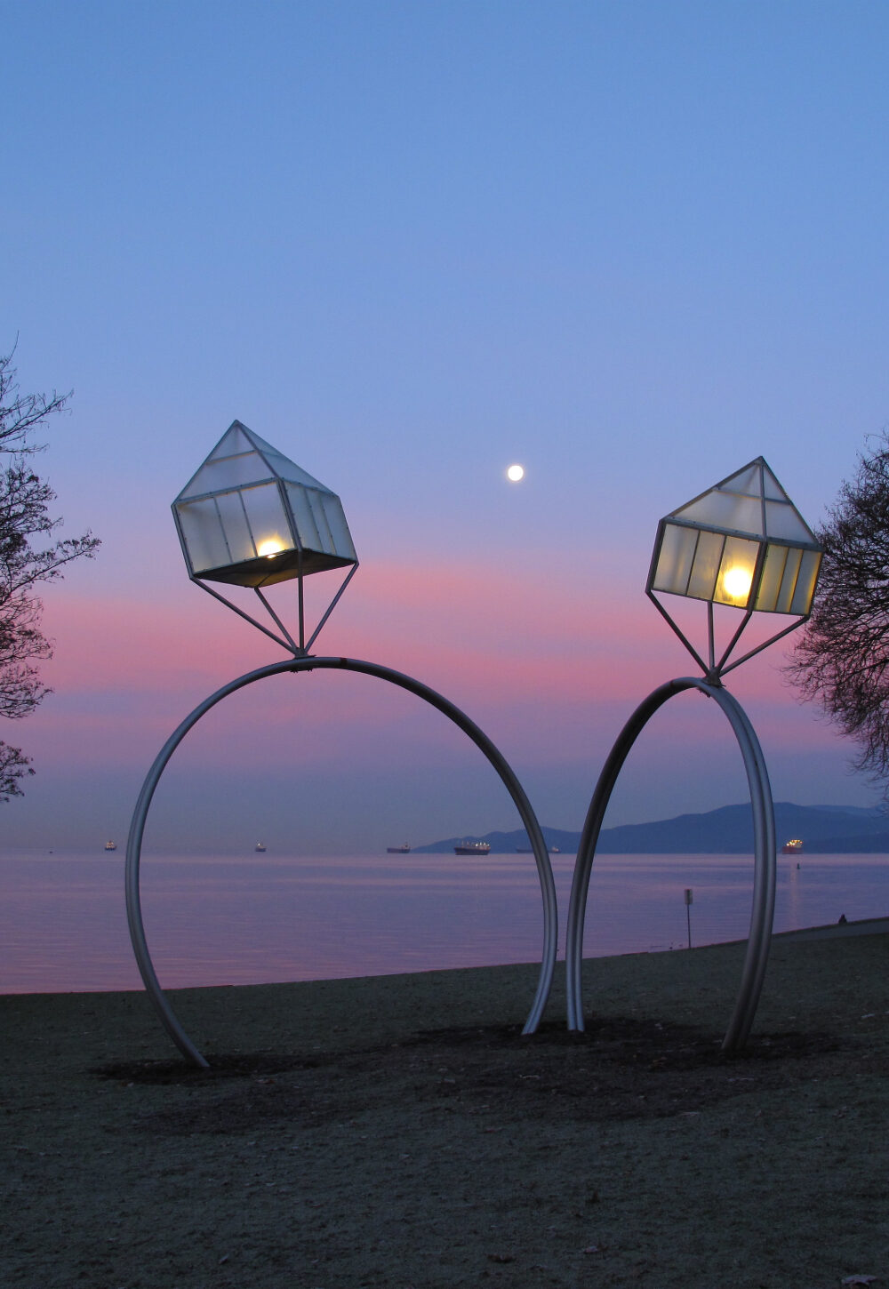 Two oversized wedding ring decorations near a lake