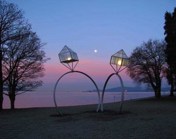 Two oversized wedding ring decorations near a lake