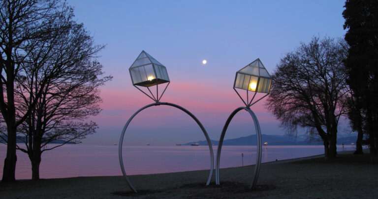 Two oversized wedding ring decorations near a lake