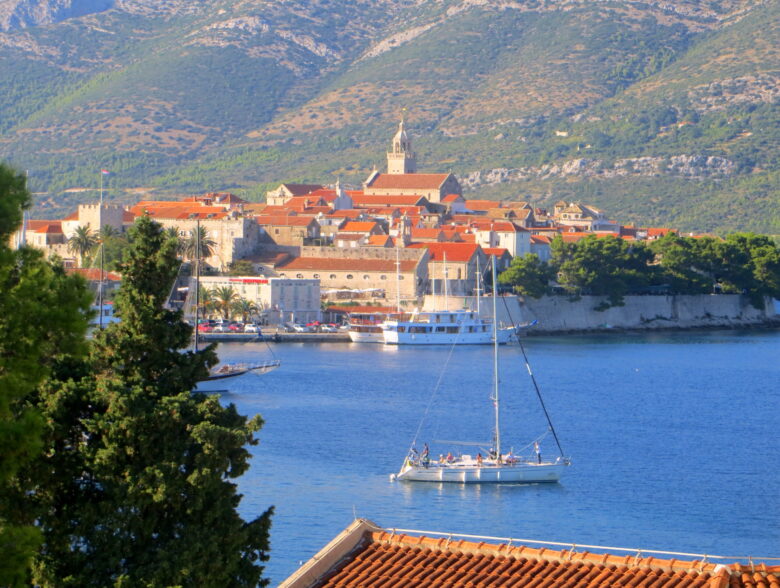 A sailing boat in the blue waters of Korcula with the old town in the background