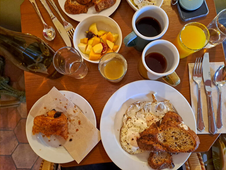 Overhead shot of eggs, toast, orange juice, pain au chocolate, fresh fruit and coffee at Hotel Amista