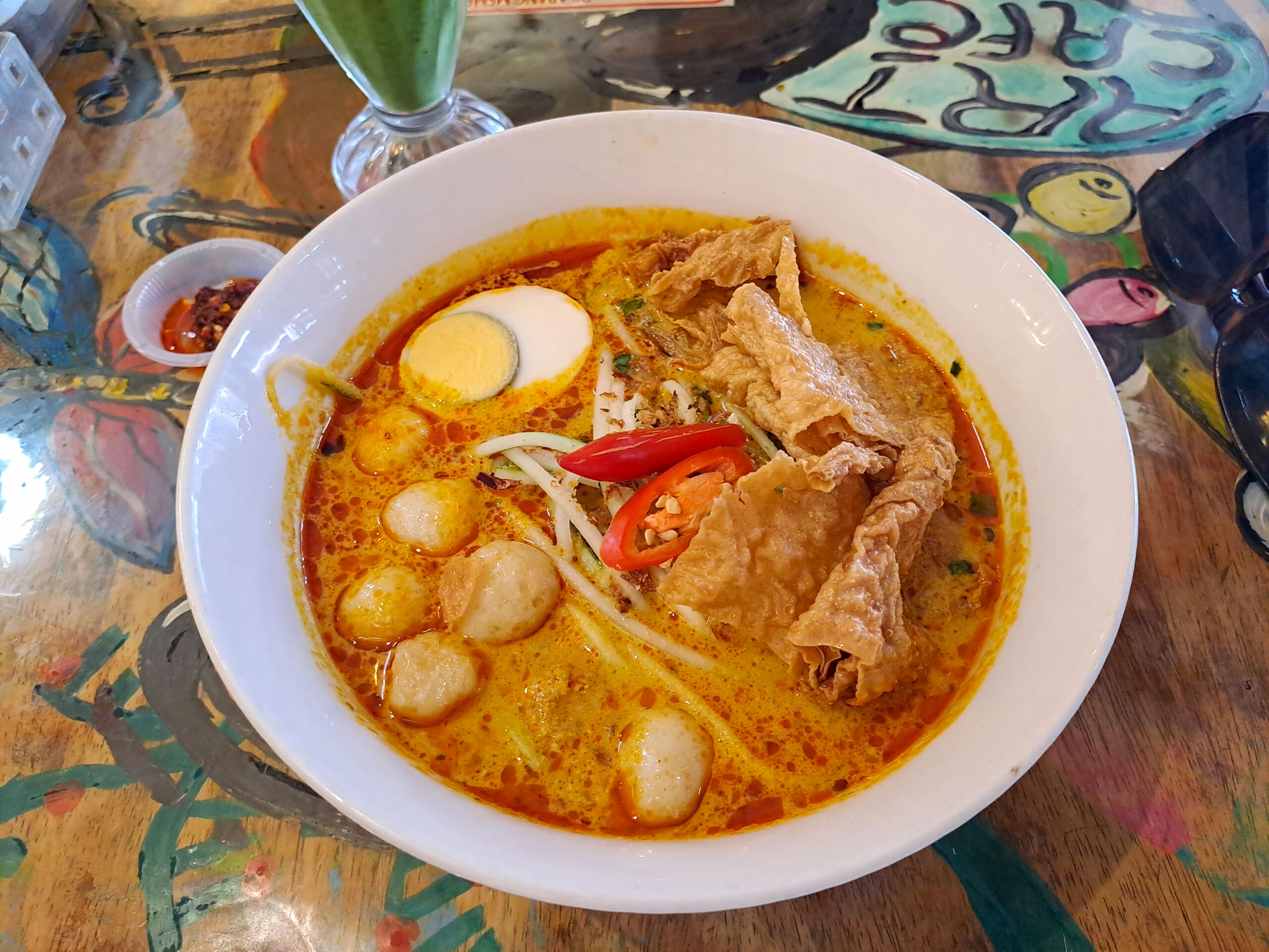 A bowl of laksa with fish balls, tofu skin, egg, beansprouts and chilli at Calanthe art Cafe in Melaka