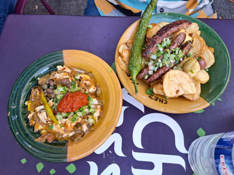 Overhead shot of a plate of kaftaji at Chez Yassine, with spicy sausages, chips and fried pepper