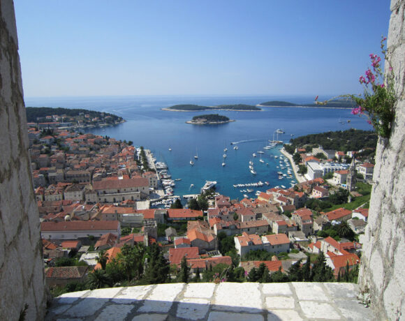 View out to blue sea and sailboats through a window in a historic building in Croatia