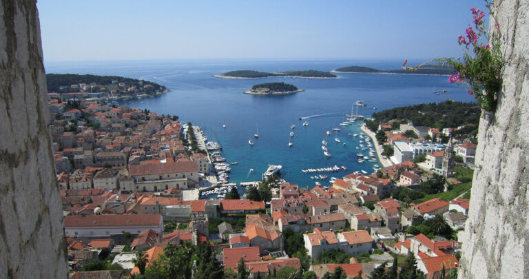 View out to blue sea and sailboats through a window in a historic building in Croatia