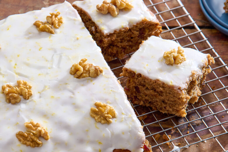 Closeup of a slice of Iced Date and Walnut Traybake Cake on a cooling rack